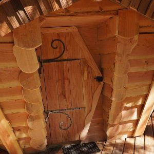 Cabane en bois dans les arbres en Auvergne, avec une porte en fer forgé décorative.