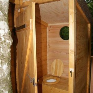 Cabane en bois perchée, avec toilettes écologiques et vue sur la nature environnante.