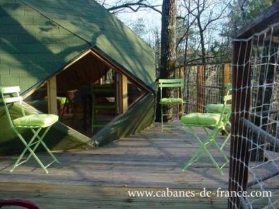 Cabane perchée en Nouvelle-Aquitaine avec chaises vertes sur une terrasse en bois.