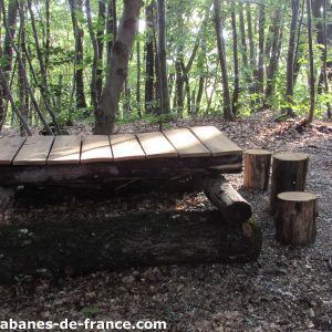 Cabanes en bois dans les bois, avec une plateforme et des troncs comme sièges.