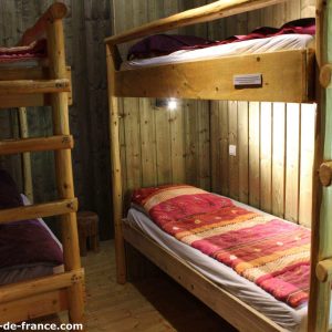 Chambre en cabane avec lits superposés en bois, décor chaleureux et naturel.