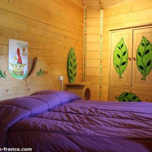 Chalet en bois coloré avec lit violet et décoration florale, Nouvelle-Aquitaine.