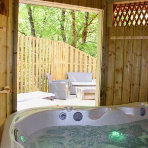 Cabane en bois en Nouvelle-Aquitaine avec jacuzzi et terrasse en bois.