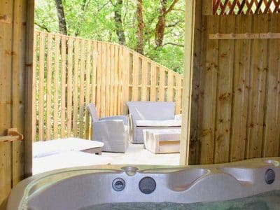Cabane en bois en Nouvelle-Aquitaine avec jacuzzi et terrasse en bois.
