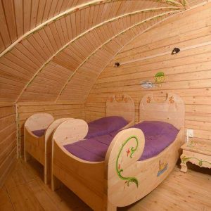 Cabanes en bois à Nouvelle-Aquitaine, avec lits en bois sculpté et ambiance chaleureuse.