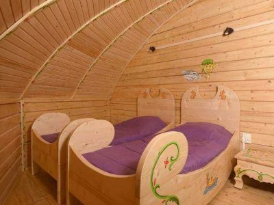 Cabanes en bois à Nouvelle-Aquitaine, avec lits en bois sculpté et ambiance chaleureuse.