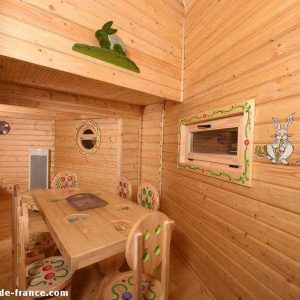 Cabane en bois colorée avec décorations ludiques et mobilier en bois.