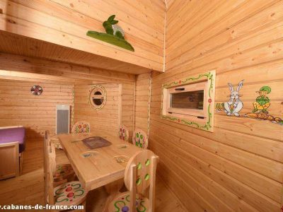 Cabane en bois colorée avec décorations ludiques et mobilier en bois.