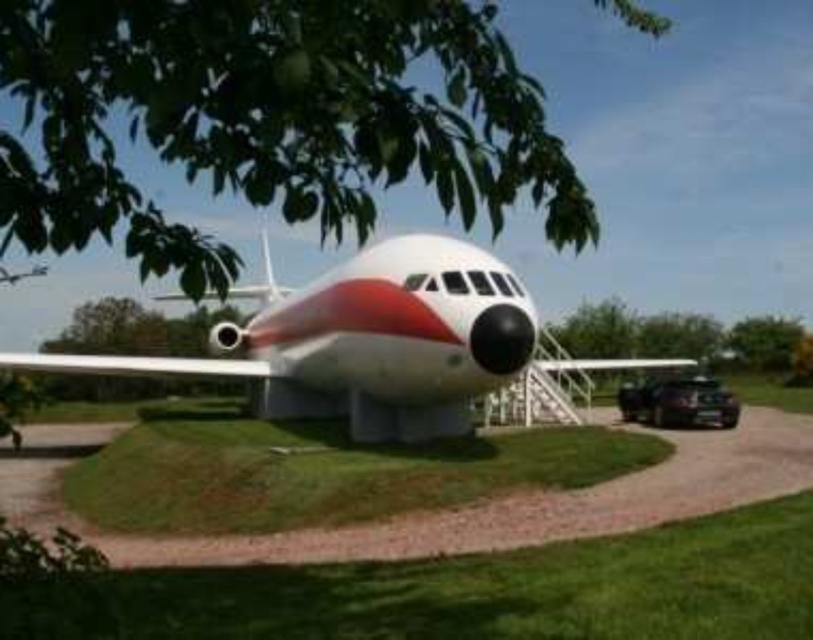 Hébergement insolite en avion à Grand-Est, entouré de verdure et dun parking.