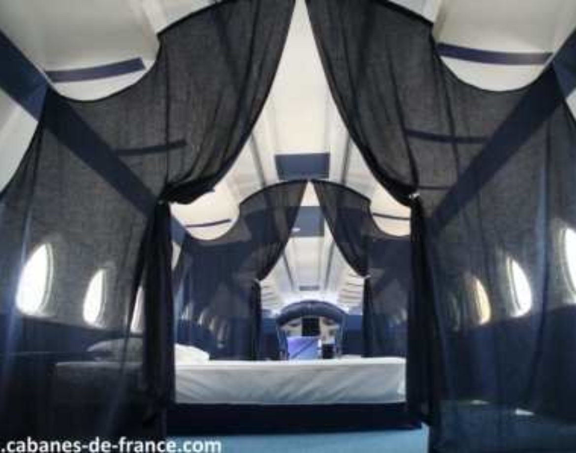 Intérieur dune cabane insolite à Grand-Est, avec des rideaux noirs et des fenêtres arrondies.