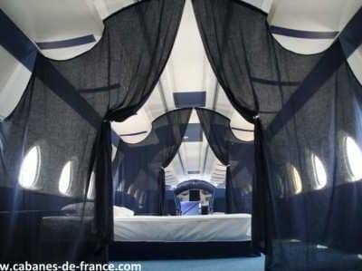 Intérieur dune cabane insolite à Grand-Est, avec des rideaux noirs et des fenêtres arrondies.