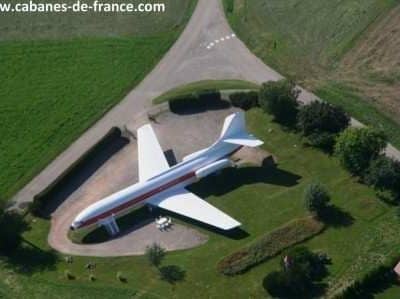 Hébergement insolite : avion reconverti en gîte, entouré de verdure.