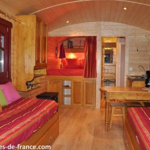 Hébergement insolite en cabane en bois, intérieur chaleureux avec lits colorés.