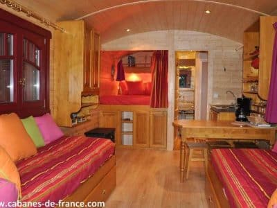 Hébergement insolite en cabane en bois, intérieur chaleureux avec lits colorés.