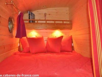 Cabane en bois cosy à Champagne-Ardenne, avec des coussins rouges et une ambiance chaleureuse.