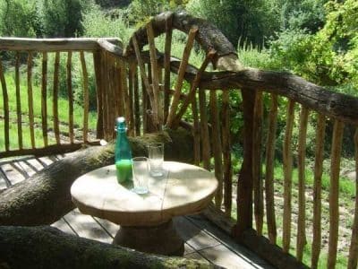 Cabane en bois dans le Limousin, avec une terrasse en rondins et vue sur la nature.