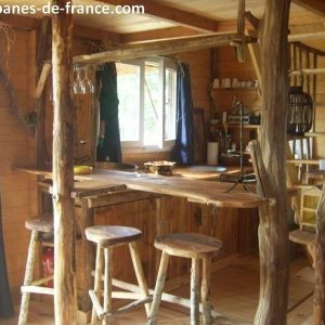 Cabane en bois dans le Limousin, avec un bar en bois rustique et des tabourets.