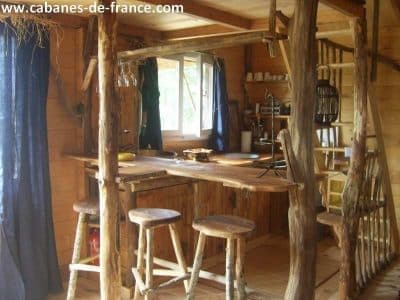 Cabane en bois dans le Limousin, avec un bar en bois rustique et des tabourets.