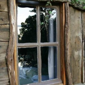Cabane en bois dans le Limousin, fenêtre rustique avec des branches décoratives.