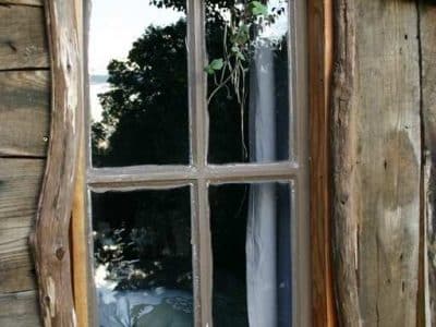 Cabane en bois dans le Limousin, fenêtre rustique avec des branches décoratives.