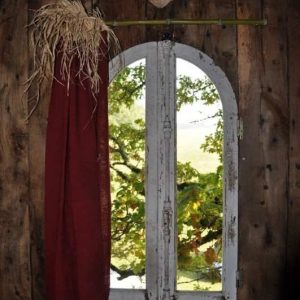 Cabane en bois dans le Limousin, avec une fenêtre arquée et rideau rouge.