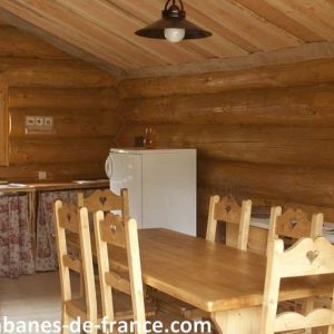 Cabane en bois en Auvergne, avec une table en bois et des chaises rustiques.