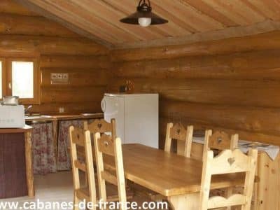 Cabane en bois en Auvergne, avec une table en bois et des chaises rustiques.