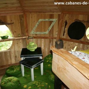 Cabane dans les arbres en Pays de la Loire, intérieur en bois avec décor verdoyant.
