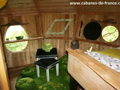 Cabane dans les arbres en Pays de la Loire, intérieur en bois avec décor verdoyant.