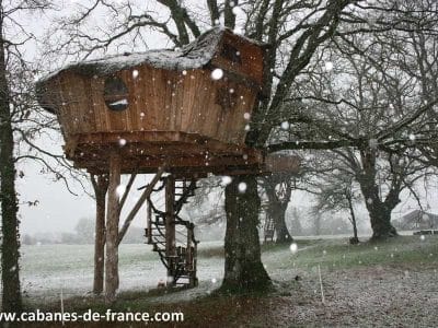 Cabane dans les arbres en bois, perchée, sous la neige dans le Pays de la Loire.