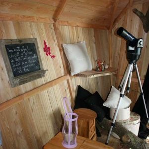 Cabane en bois cosy avec un télescope et des coussins confortables.