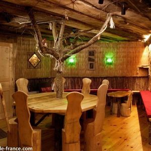 Cabane en bois avec une grande table ronde et un arbre décoratif au centre.