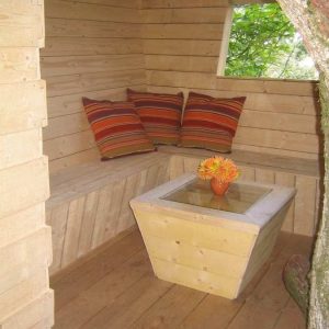 Cabane en bois dans les Pays de la Loire, avec coussins colorés et table en verre.
