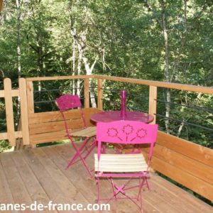 Cabane perchée en Midi-Pyrénées avec terrasse en bois et mobilier coloré.