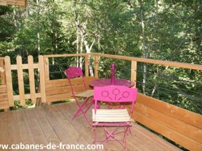 Cabane perchée en Midi-Pyrénées avec terrasse en bois et mobilier coloré.