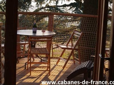 Cabane perchée en Auvergne, avec terrasse en bois et vue dégagée sur la nature.