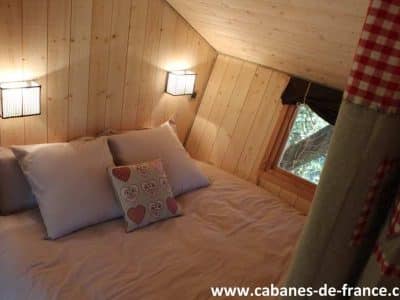 Chalet en bois chaleureux avec lit douillet et éclairage doux, en Auvergne-Rhône-Alpes.