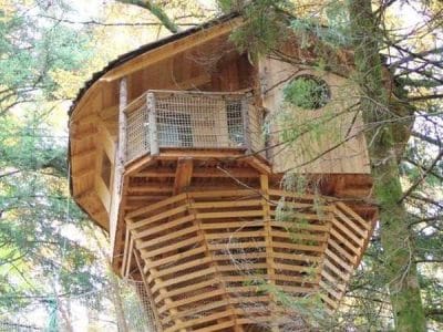 Cabane perchée dans les arbres, en bois, entourée de verdure en Bourgogne-Franche-Comté.