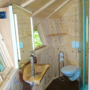 Cabane en bois avec salle de bain moderne, vue sur la nature environnante.