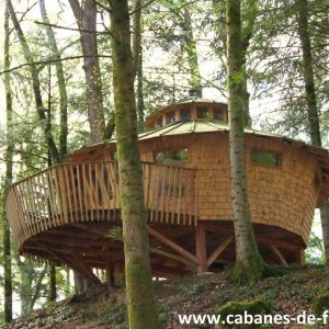 Cabane perchée en bois dans les arbres, entourée de verdure en Bourgogne-Franche-Comté.