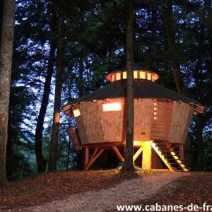 Cabane perchée en bois, illuminée, nichée dans la forêt de Bourgogne-Franche-Comté.