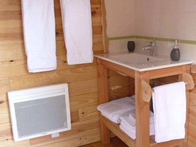 Hébergement insolite en bois à Limousin, avec salle de bain moderne et serviettes blanches.