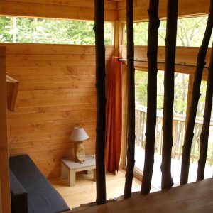 Cabane en bois dans les arbres, avec vue sur la nature et des murs en bois chaleureux.