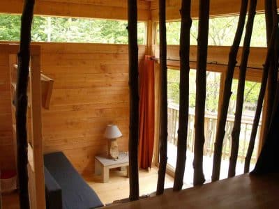 Cabane en bois dans les arbres, avec vue sur la nature et des murs en bois chaleureux.