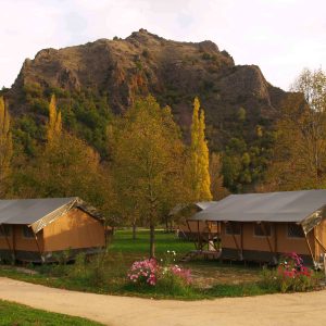 Tentes safari en Auvergne, entourées de montagnes et darbres colorés.