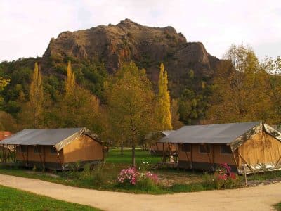 Tentes safari en Auvergne, entourées de montagnes et darbres colorés.
