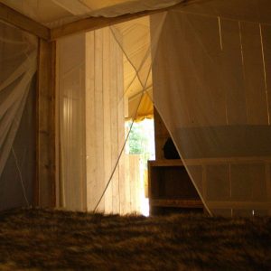Hébergement insolite en Auvergne : cabane en bois avec moustiquaire et vue sur la nature.