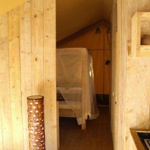 Hébergement insolite en Auvergne : cabane en bois avec lit à baldaquin et décor chaleureux.