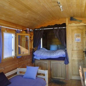 Intérieur chaleureux dune roulotte en bois, avec lit douillet et décor rustique.