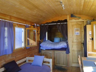 Intérieur chaleureux dune roulotte en bois, avec lit douillet et décor rustique.